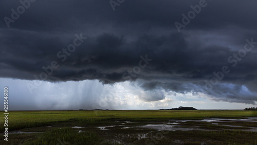 Dark storm and rain over salt water marsh © mary