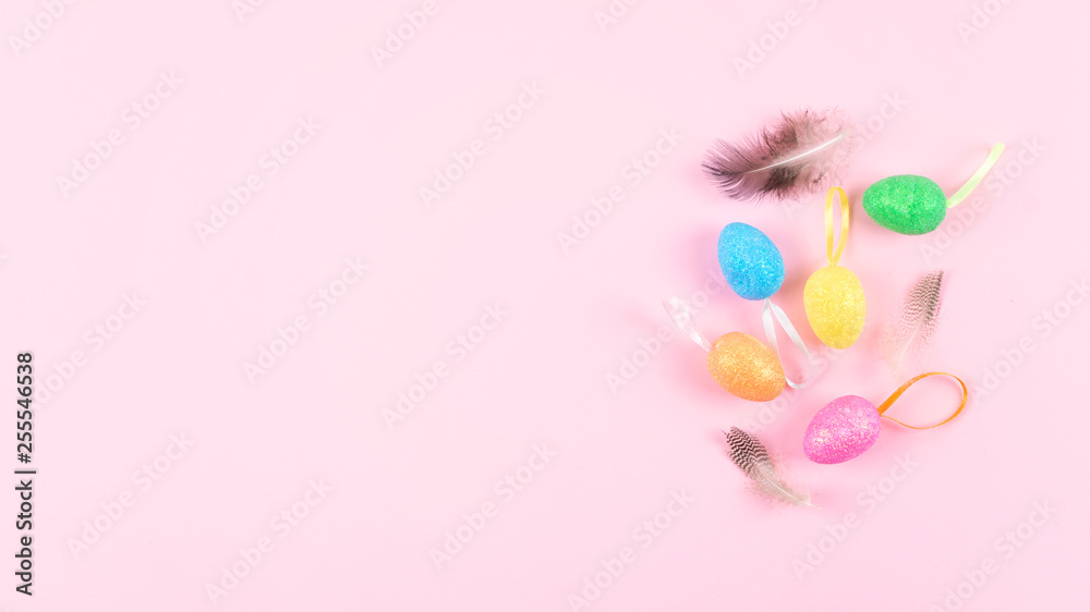 Decorative Easter eggs with feathers on pink background. Easter composition, greeting card with multicolored decorative eggs pastel rose background