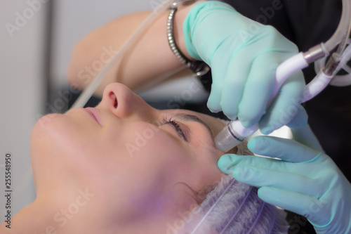 Close-up view of female face having facial cleansing or dermabrasion treatment at beauty salon.