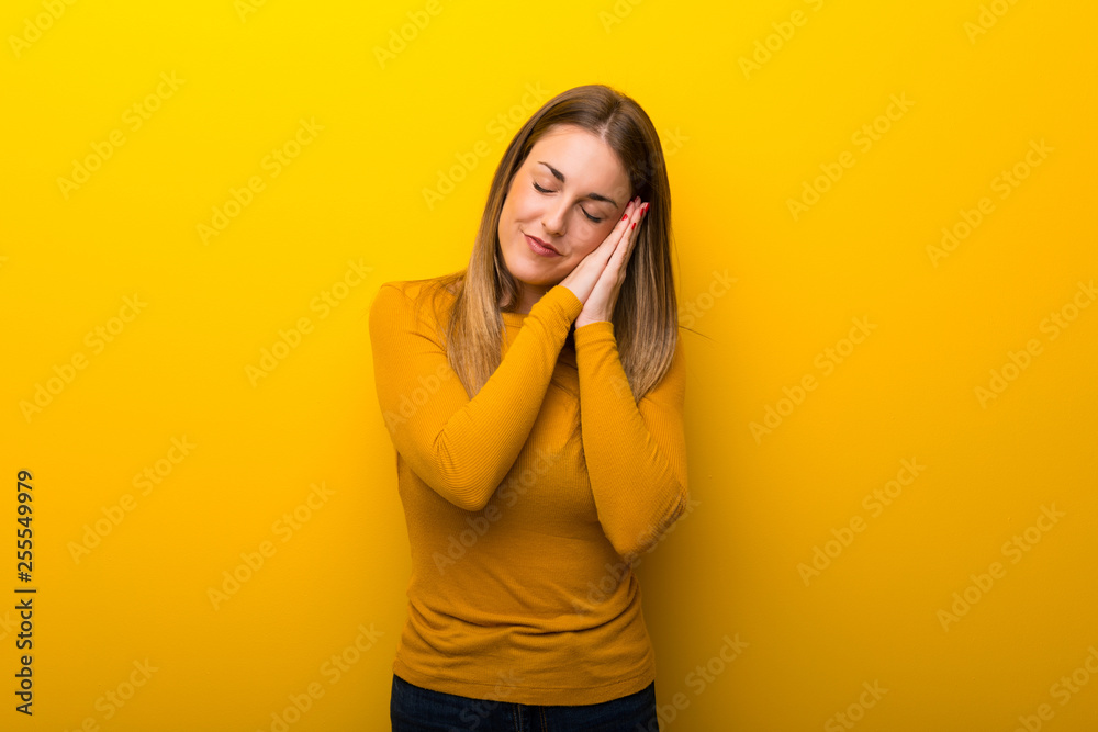 Young woman on yellow background making sleep gesture in dorable expression Young woman on yellow background making sleep gesture in dorable expression