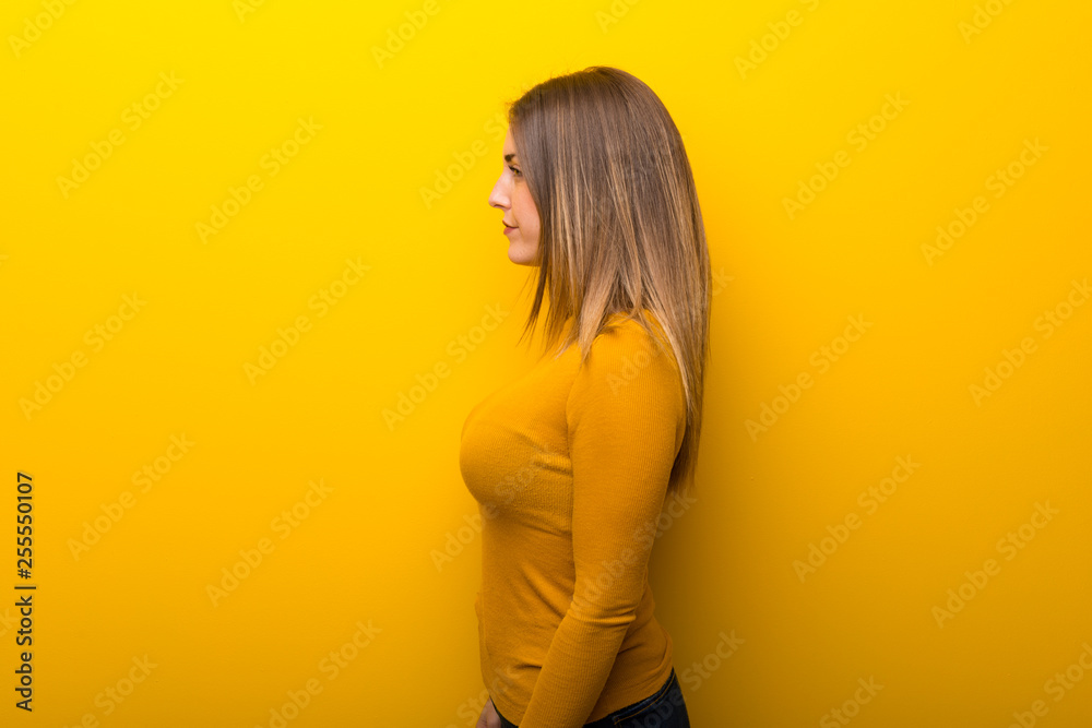 Fototapeta premium Young woman on yellow background in lateral position