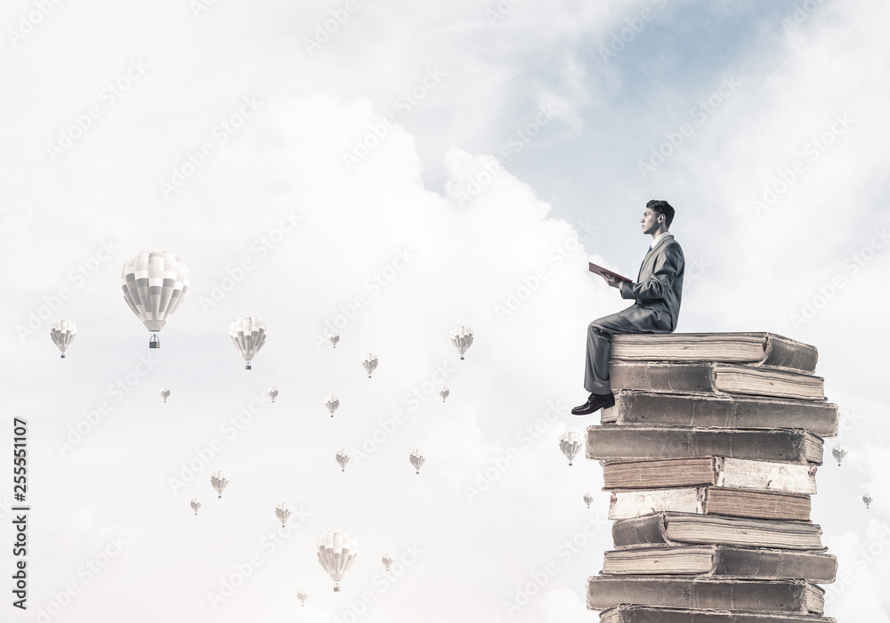 Man student reading book and aerostats flying around in air Man student reading book and aerostats flying around in air