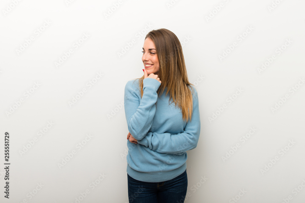 Blonde woman on isolated white background looking to the side with the hand on the chin Blonde woman on isolated white background looking to the side with the hand on the chin