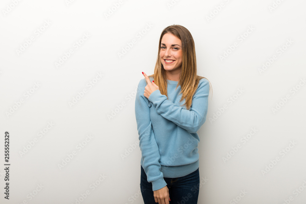 Blonde woman on isolated white background pointing to the side to present a product Blonde woman on isolated white background pointing to the side to present a product