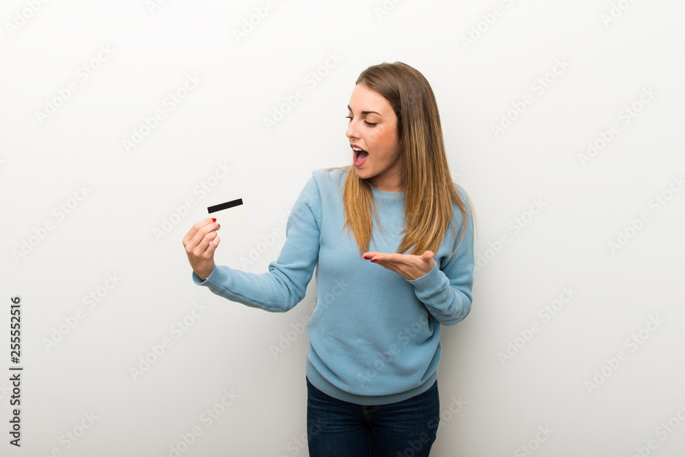 Blonde woman on isolated white background holding a credit card and surprised Blonde woman on isolated white background holding a credit card and surprised