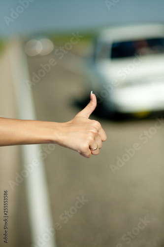 close - up of a woman's hand with raised thumb hitchhiking car