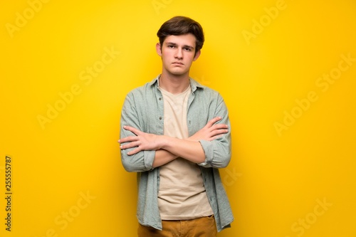 Teenager man over yellow wall portrait