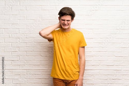 Teenager man over white brick wall having doubts