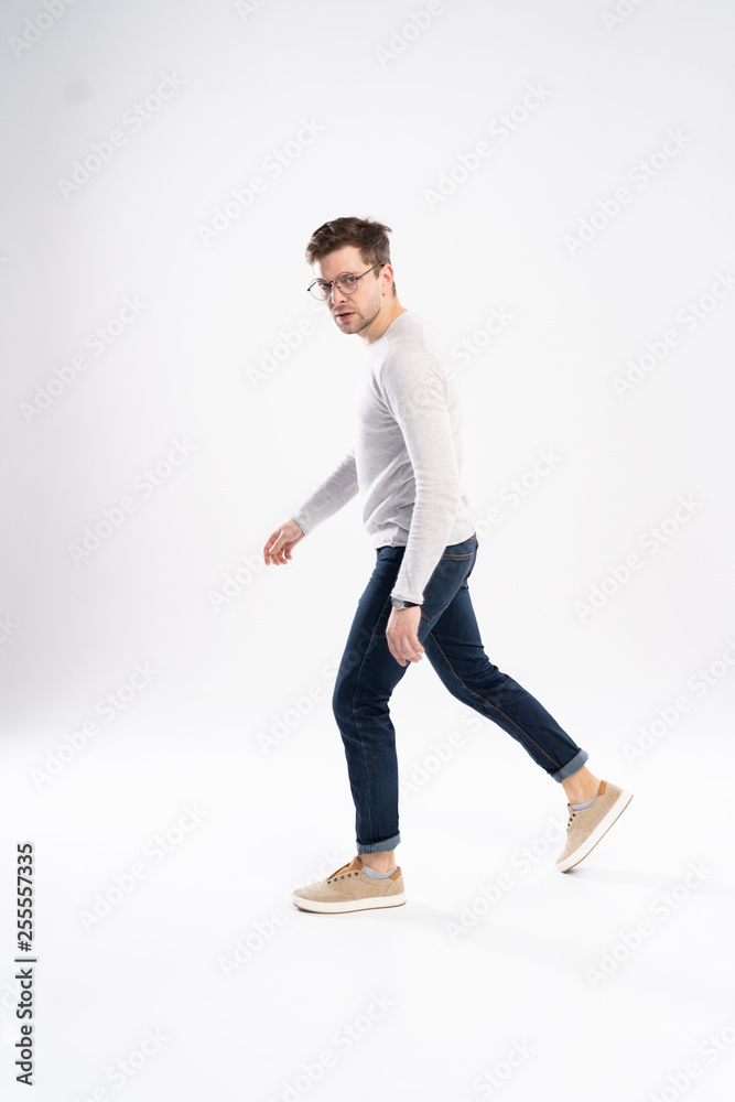 Side view of a young fashion man walking on isolated background.