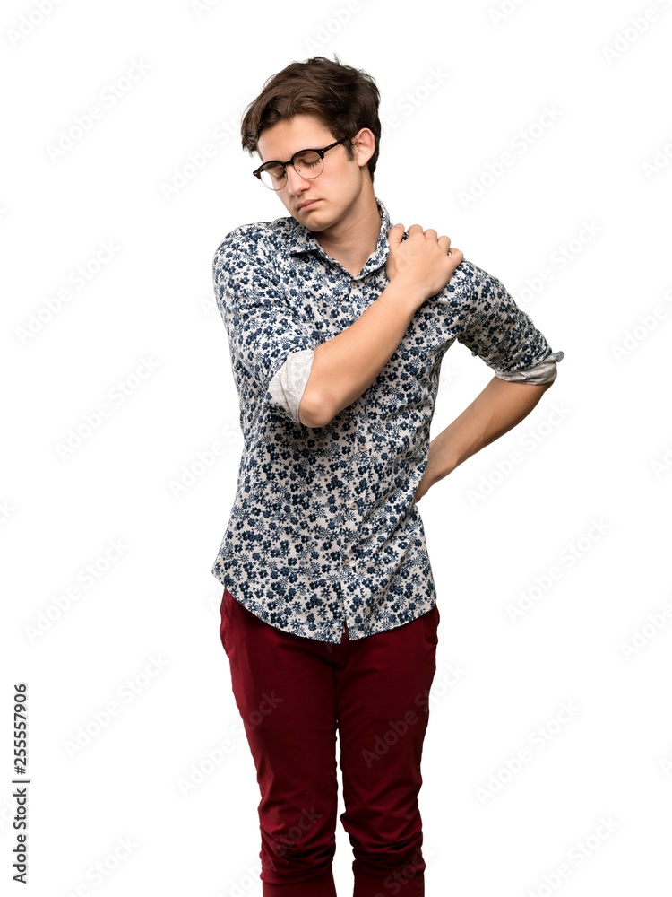 Teenager man with flower shirt and glasses suffering from pain in shoulder for having made an effort over isolated white background Teenager man with flower shirt and glasses suffering from pain in shoulder for having made an effort over isolated white background