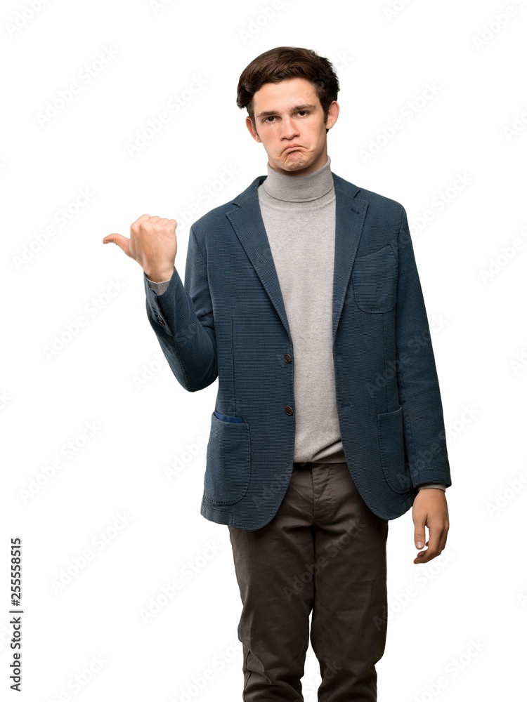 Teenager man with turtleneck unhappy and pointing to the side over isolated white background Teenager man with turtleneck unhappy and pointing to the side over isolated white background