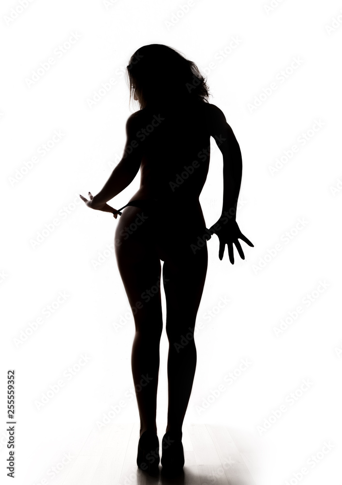 silhouette of a full-length beautiful nude woman in a small panties and high heels
