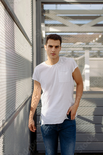 Beautiful caucasian man in white t-shirt and blue jeans stay on the street 