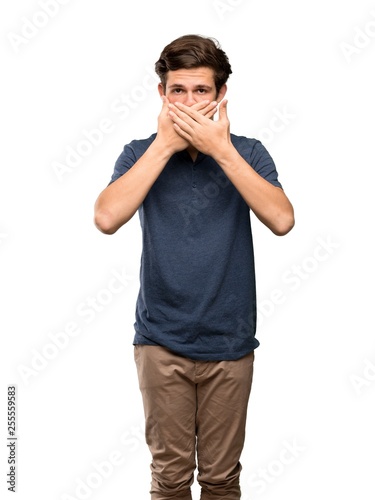 Teenager man covering mouth with hands for saying something inappropriate over isolated white background © luismolinero