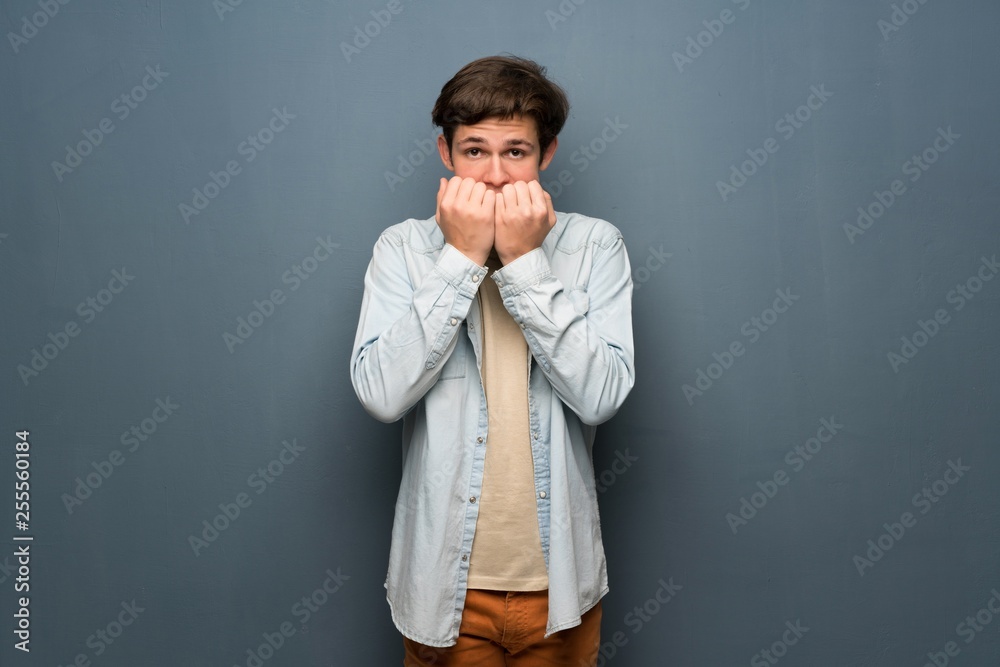 Teenager man with jean jacket over grey wall nervous and scared putting hands to mouth Teenager man with jean jacket over grey wall nervous and scared putting hands to mouth