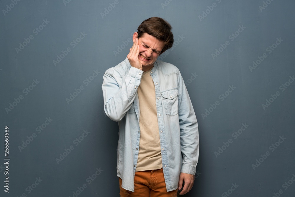 Fototapeta premium Teenager man with jean jacket over grey wall with toothache
