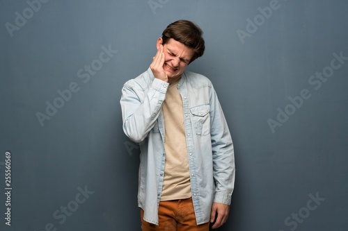 Teenager man with jean jacket over grey wall with toothache