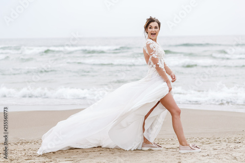 positive bride runs on the sea beach on an overcast day