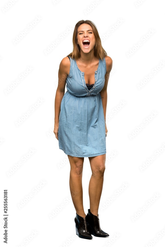 A full-length shot of a Blonde woman with jean dress shouting to the front with mouth wide open over isolated white background A full-length shot of a Blonde woman with jean dress shouting to the front with mouth wide open over isolated white background