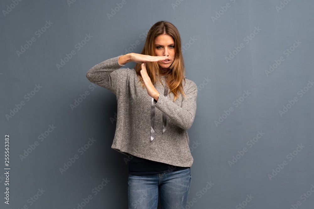 Blonde woman over grey background making time out gesture Blonde woman over grey background making time out gesture