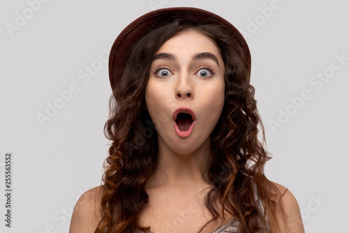 Photo of emotive young one woman, dressed in casual outfit, reacts on something shocking, has eyes popped out, isolated on white background in studio, recieves bad news