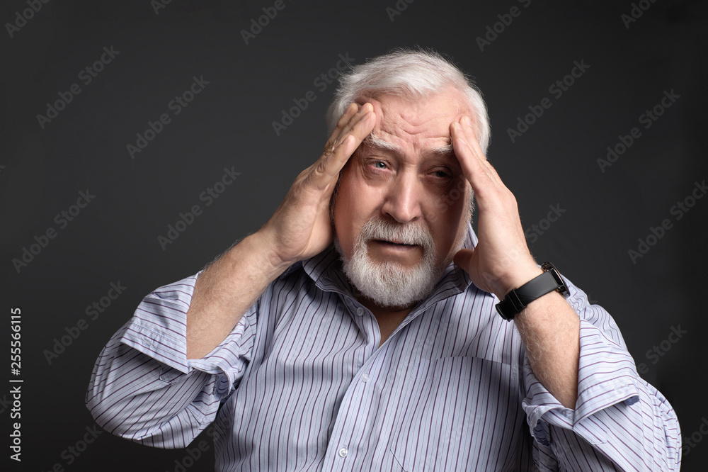business, gray-haired man holding his head with two hands on a gray background. Headache business, gray-haired man holding his head with two hands on a gray background. Headache
