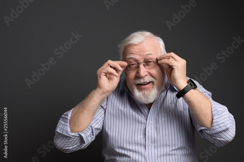 charismatic, gray-haired man holds his glasses and smiles