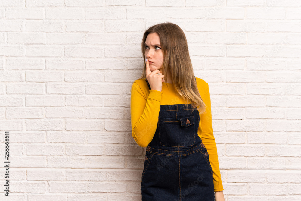 Teenager girl over white brick wall having doubts and thinking Teenager girl over white brick wall having doubts and thinking