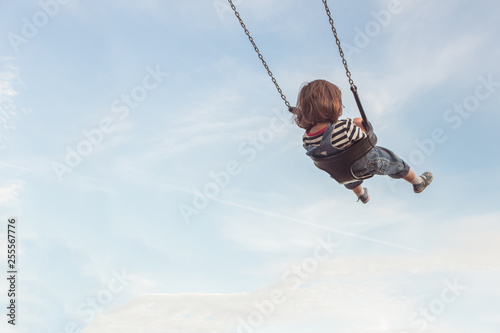 Poster Kleines Mädchen auf einer Schaukel und einem blauen Himmel mit  einigen Wolken. - Nikkel-Art.de