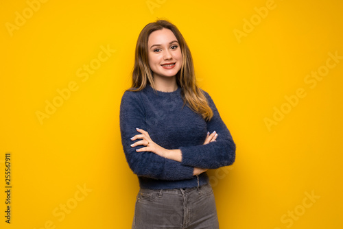 Teenager girl over yellow wall keeping the arms crossed in frontal position