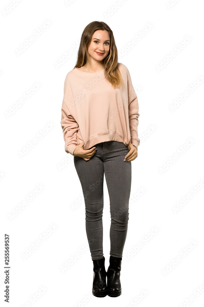 A full-length shot of a Teenager girl with pink sweater laughing looking to the front over isolated white background A full-length shot of a Teenager girl with pink sweater laughing looking to the front over isolated white background