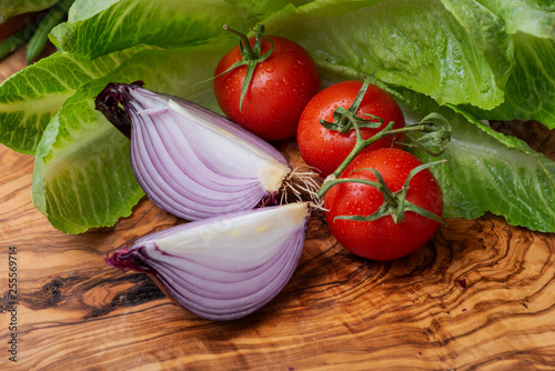 Red Onion cut into wedges and Organic Red Tomatoes on the vine arranged on natural olive wood.