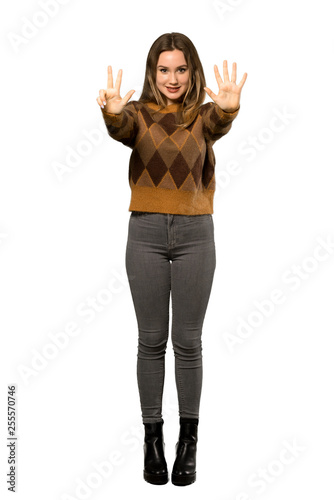 A full-length shot of a Teenager girl with brown sweater counting eight with fingers over isolated white background