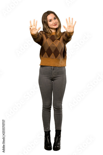 A full-length shot of a Teenager girl with brown sweater counting nine with fingers over isolated white background