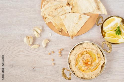 Homemade hummus with olive oil on a light background. Arabic bread on a wooden board