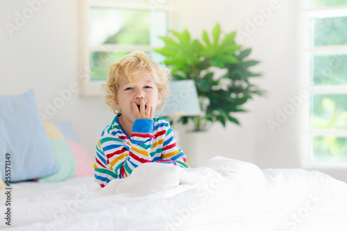 Child playing in bed. Kids room. Baby boy at home.