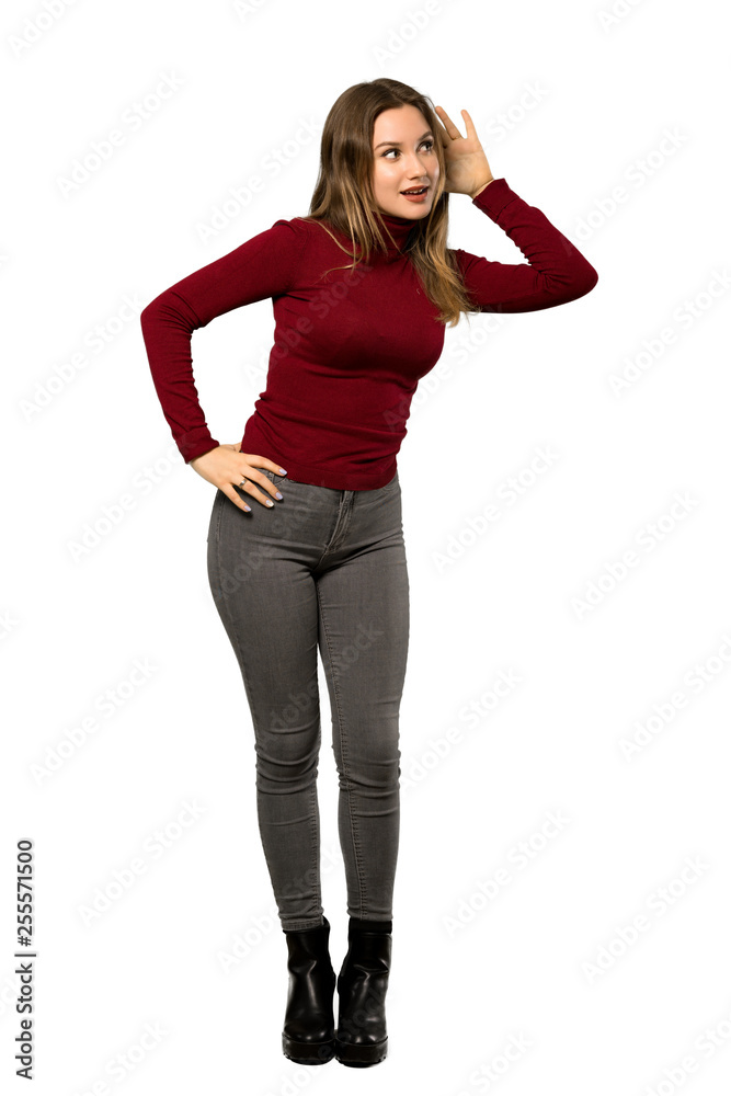 A full-length shot of a Teenager girl with turtleneck listening to something by putting hand on the ear over isolated white background A full-length shot of a Teenager girl with turtleneck listening to something by putting hand on the ear over isolated white background