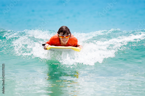 Canvas Print Child surfing on tropical beach. Surfer in ocean.