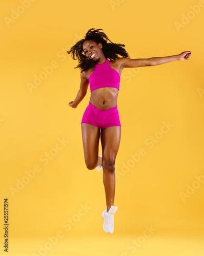 Sporty fit black skin woman, athlete makes fitness exercising on dark background.