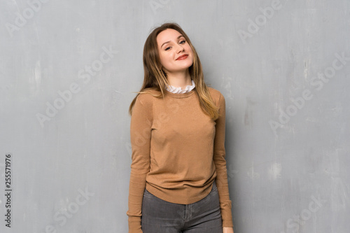 Teenager girl over textured wall smiling a lot