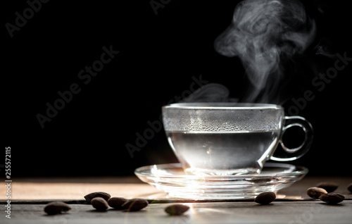 Warm drink with steam and smoke in cup on black background.