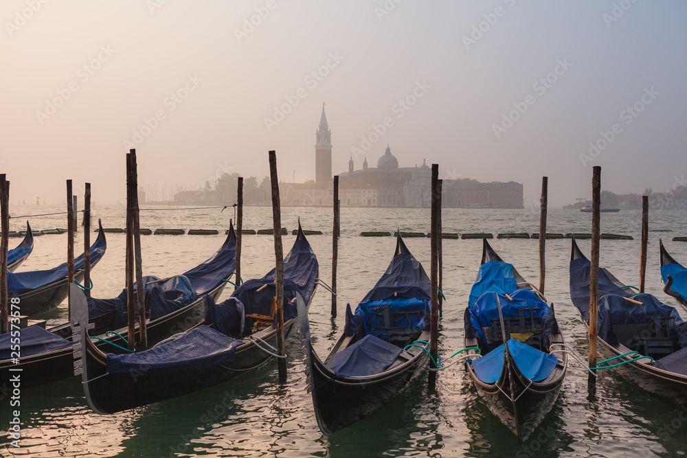 Venetian foggy morning and gondolas on the Cathedral of San Giorgio Maggiore as a background