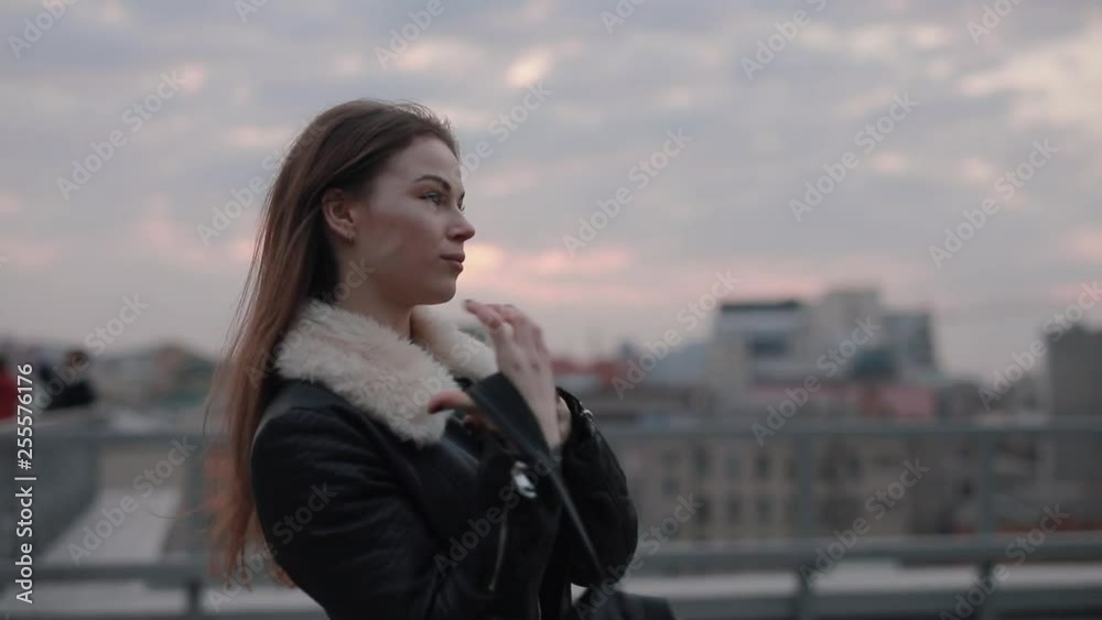 Stylish serious woman walks in the evening city, sky background Stylish serious woman walks in the evening city, sky background