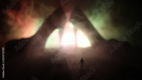Artwork decoration. Silhouette of a man standing in the middle of the road on a misty night with giant high heel women shoes. Women power or women domination concept. Selective focus