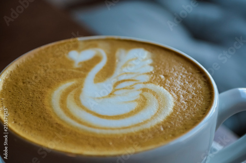 Fresh and fragrant coffee in coffee shop. A cappuccino cup with the drawing of a swan. Latte art. The invigorating drink.