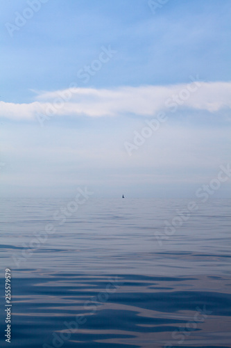 Small sailing boat between the sea and the sky
