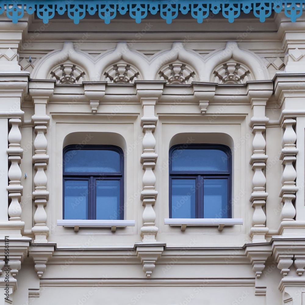 Close up view on a facade of white ancient building with decorative ornaments and two windows