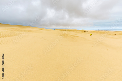 Woman with sandboard walking Giant sand dunes, Te Paki, Northland, North Island, New Zealand