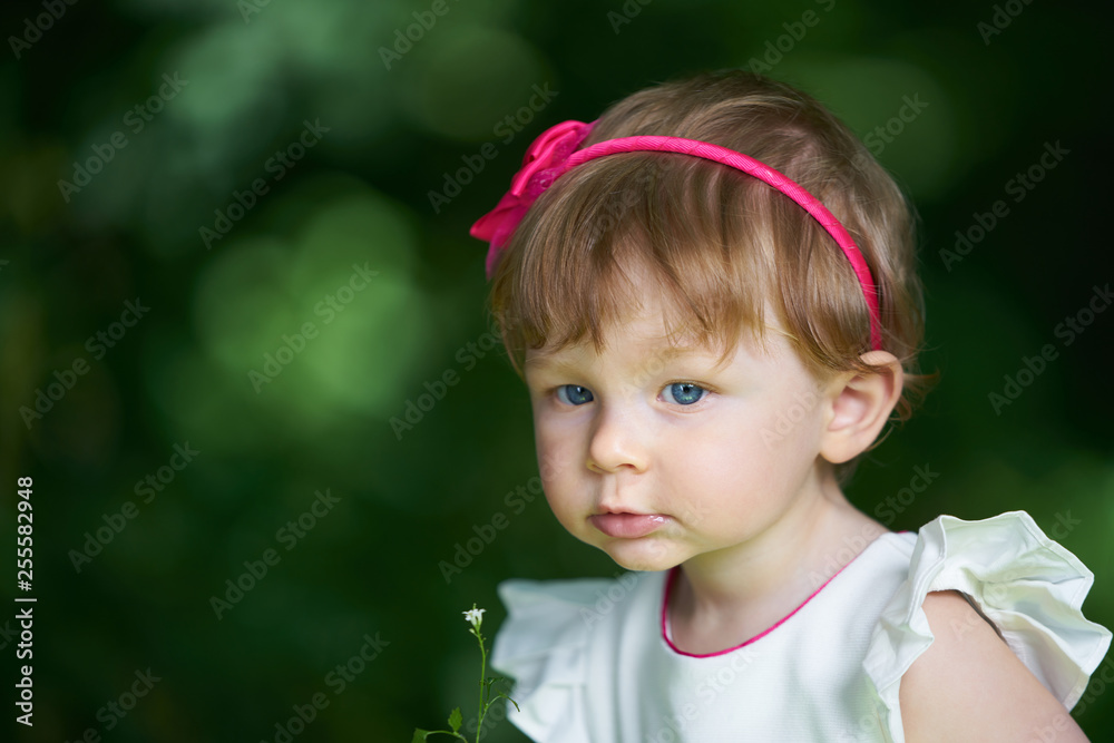 Portrait of a one-year-old girl with blue eyes and hair decoration looking aside Portrait of a one-year-old girl with blue eyes and hair decoration looking aside