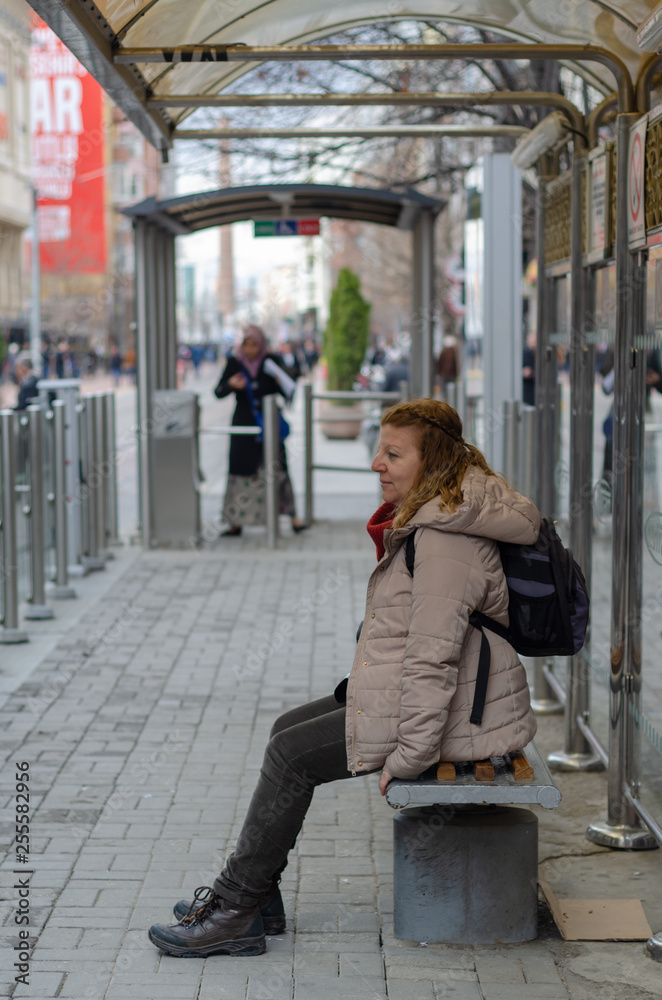 Blonde woman waiting for the tram  at the stop